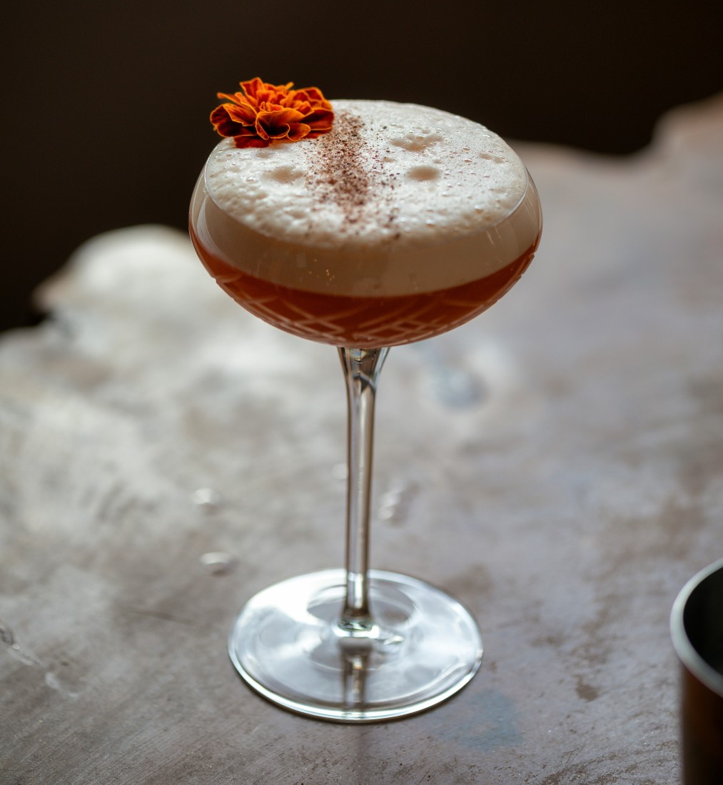 Drink autoral com espuma decorado com tagete comestível da Aflora Club